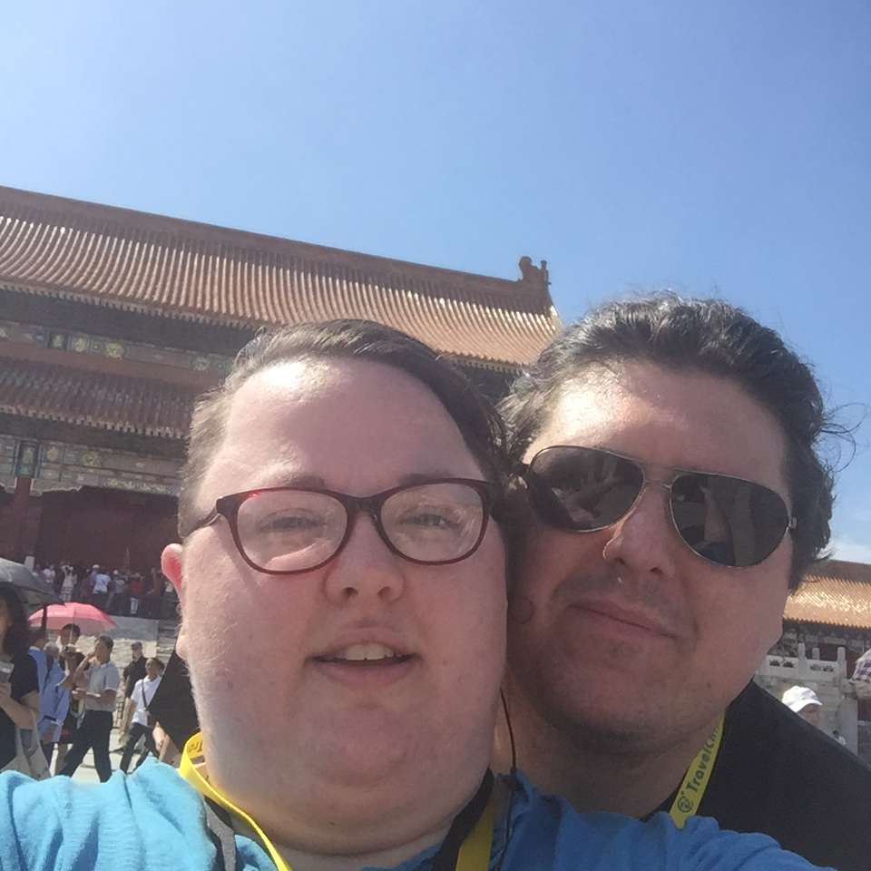 Woman at the Forbidden City in Beijing looking distracted, red palace walls and golden roofs visible behind her during website security emergency
